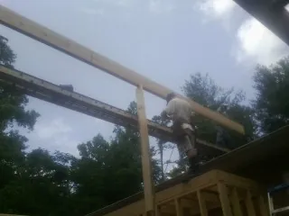 Carpenter setting a ridge beam over a new addition frame — Ice Dam Removal by Roofing Brothers in Millport