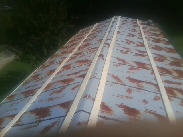 Rusted metal roof panels with new wood purlins before replacement — Storm Damage Roof Repair in Millport by Roofing Brothers