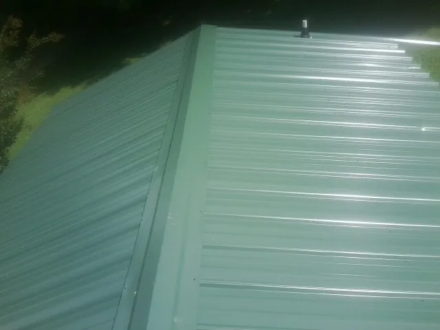 New green metal panels meeting at the ridge of a roof — Flat Roof Repair work by our crew in Millport