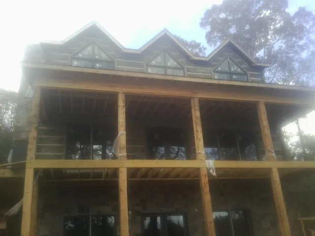 Dormers and porch framing on a large log home under construction — Roof Coating work by our crew in Millport