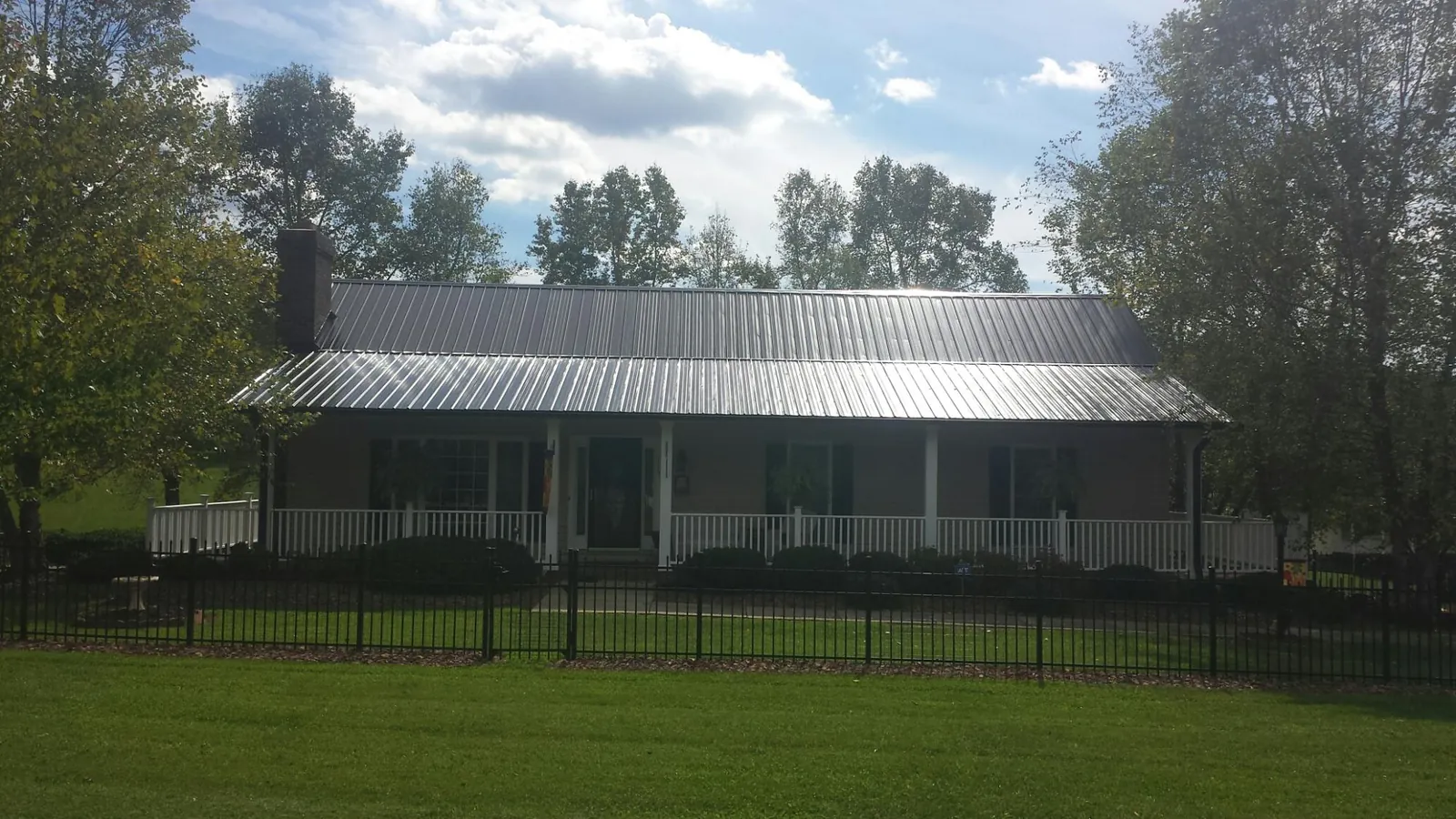 Gray metal roof on a brick ranch with a full width front porch — Gutter Guard Installation work by our crew in Millport