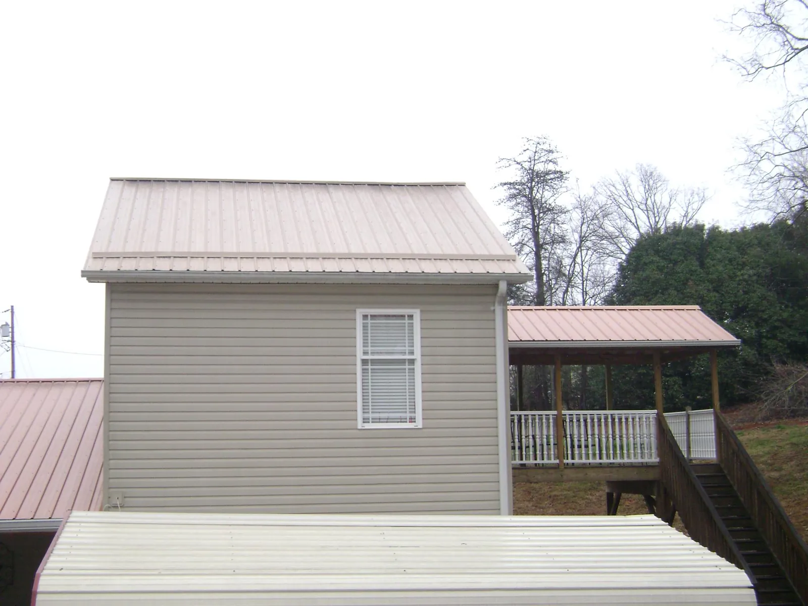 Tan metal roofs on a two story addition and attached porch, from a Roof Replacement job in Millport