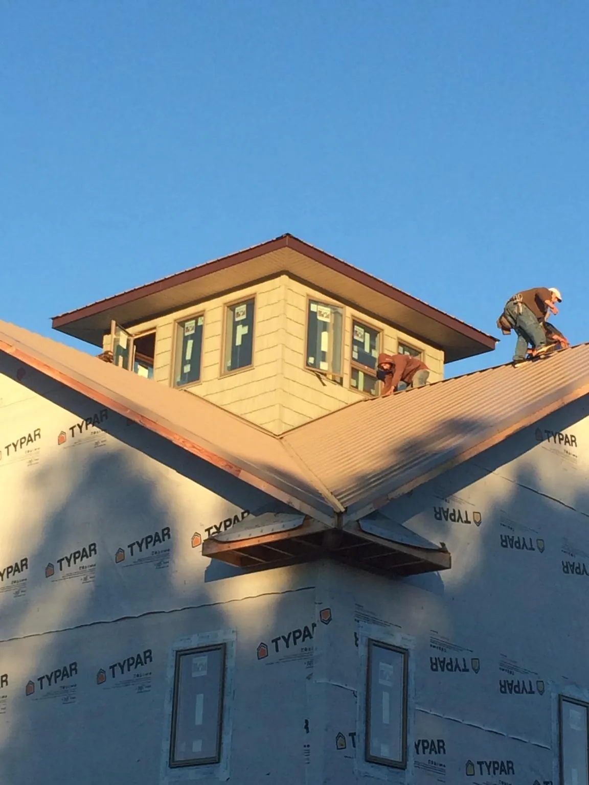 Roofers working around a rooftop cupola on a new metal roof at sunset — Roof Waterproofing in Millport by Roofing Brothers
